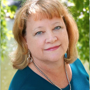 Karen is wearing an aqua blue blouse and smiling up at the camera.