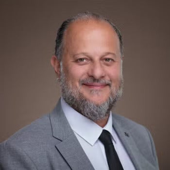 Abdul rehman chamseddine is wearing a gray suit and smiling into the camera